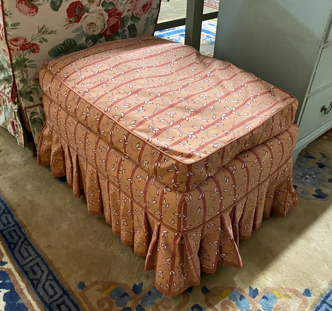 An early 20th century armchair and footstool upholstered in Colefax & Fowler printed fabric